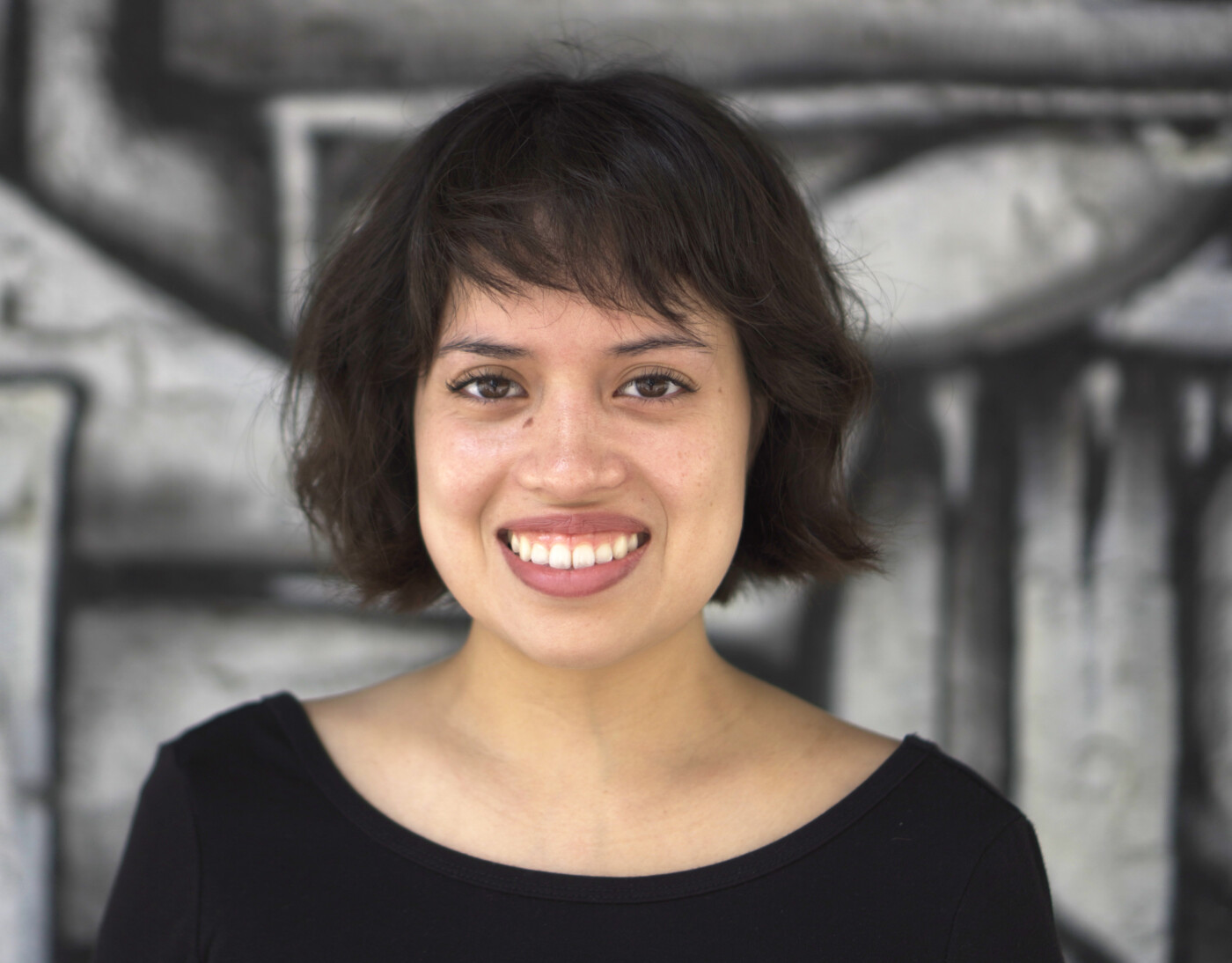 Headshot of Jocelyn Reyes, a Latin American woman with short brown hair smiles in front of a gray background.