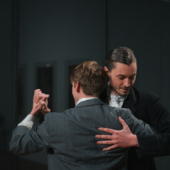 2 male dancers in suits embrace